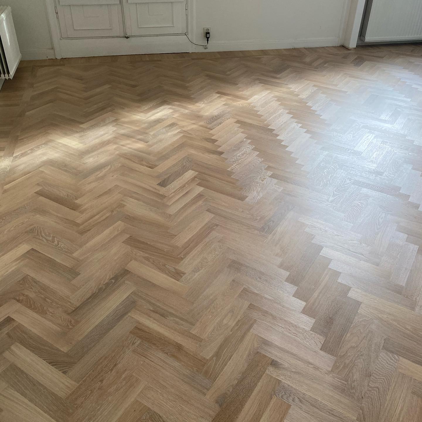 Ljus massiv fiskbensparkett i ek lagd och behandlad med vitpigment för ett modernt och stilrent resultat i Stockholm.